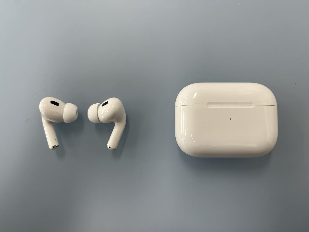 Um par de AirPods Pro branco ao lado do estojo de carregamento aberto, sobre fundo claro