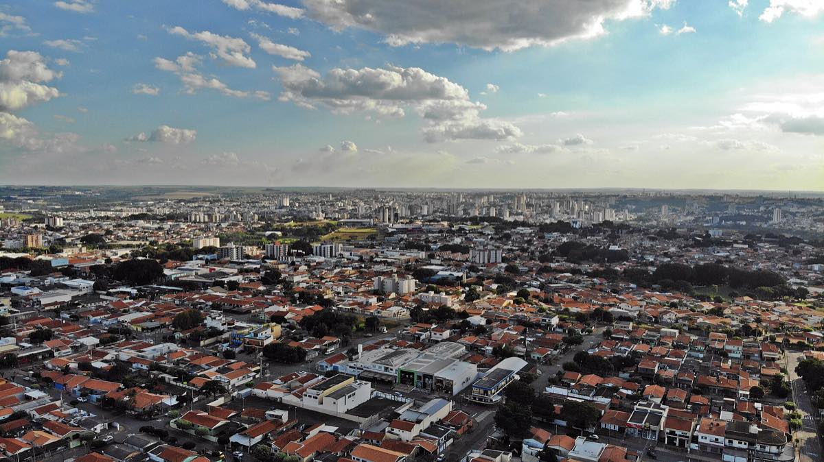 Vista aérea da cidade de Americana, em São Paulo, no fim de tarde, com bairros residenciais em primeiro plano e a região central ao fundo