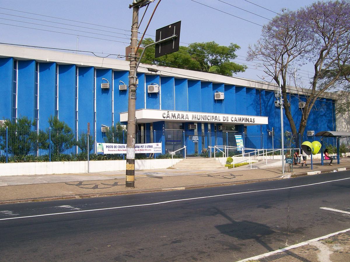 Prédio azul de dois andares visto do outro lado da avenida, com o letreiro CÂMARA MUNICIPAL DE CAMPINAS em letras metálicas sobre a marquise da entrada.