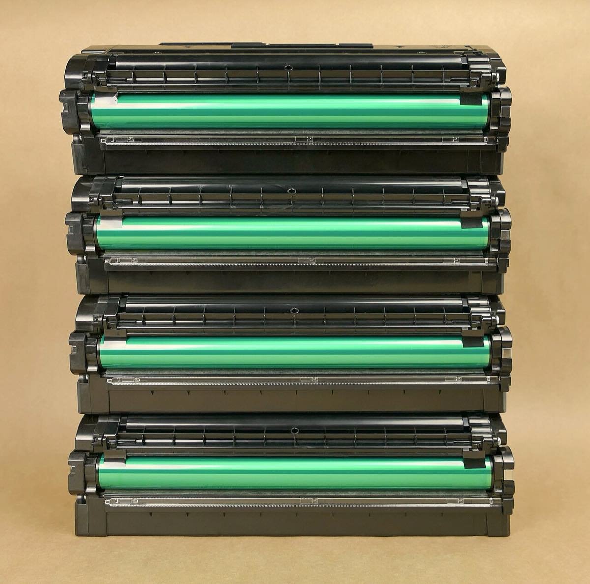 Quatro cartuchos de cilindro para impressora a laser empilhados, com os rolos verdes visíveis
