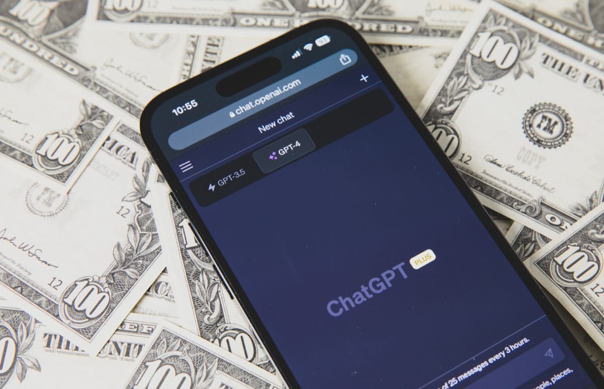 Um smartphone com o aplicativo do ChatGPT aberto, apoiado sobre notas de dólar americano
