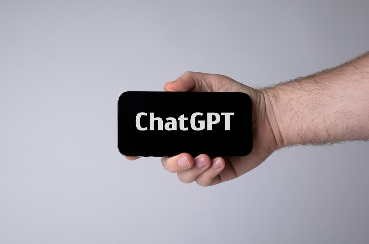 Mão segurando um smartphone com o aplicativo ChatGPT aberto na tela