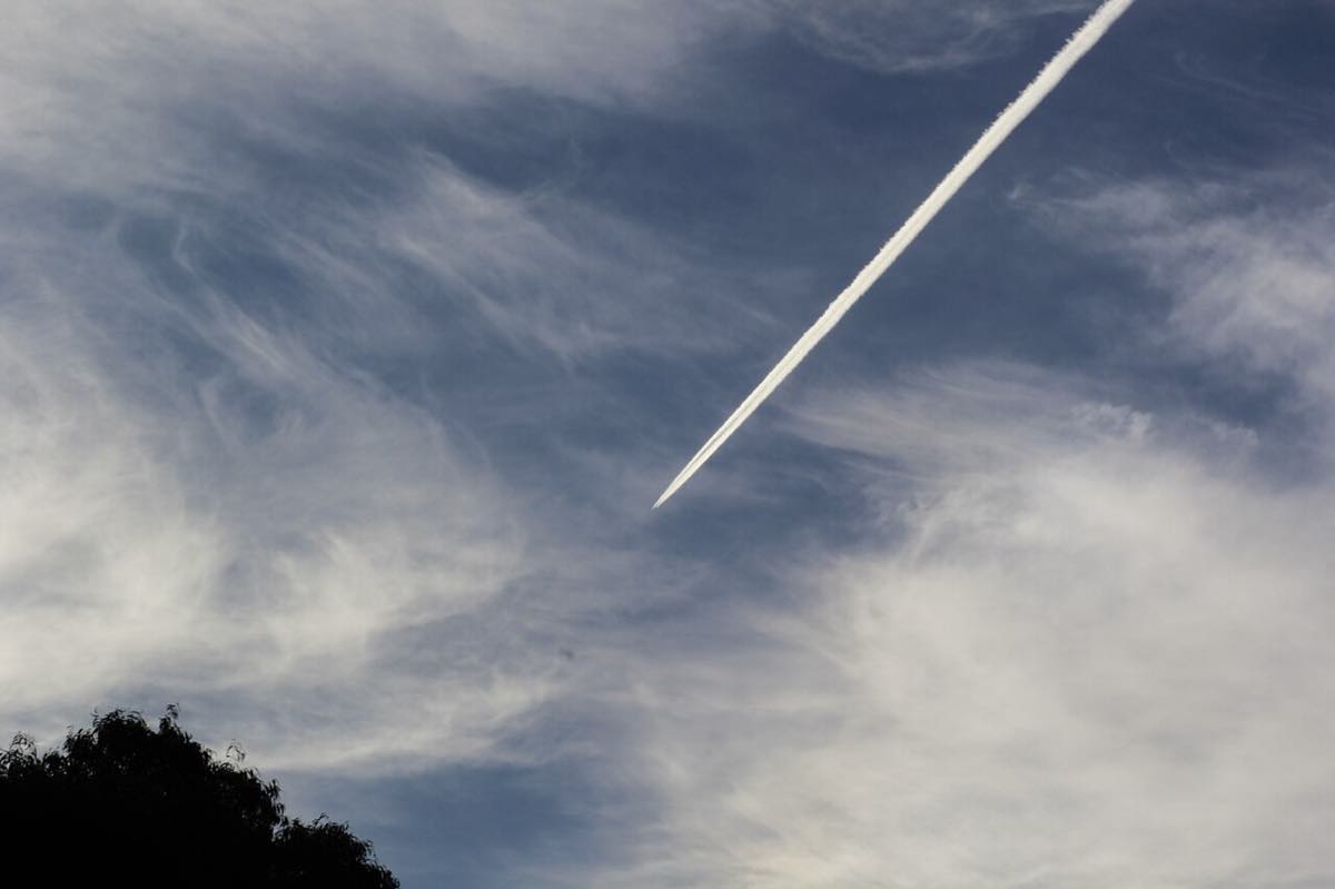 Rastro de condensação branco deixado por um avião a jato cruzando um céu azul.