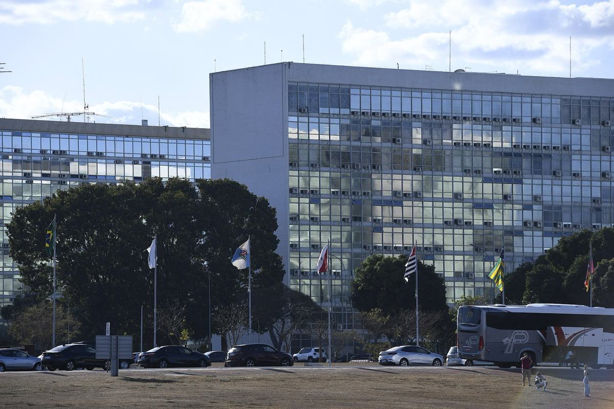 Vista da Esplanada dos Ministérios em Brasília, com os blocos de concreto enfileirados dos dois lados do gramado central e o Congresso Nacional ao fundo.