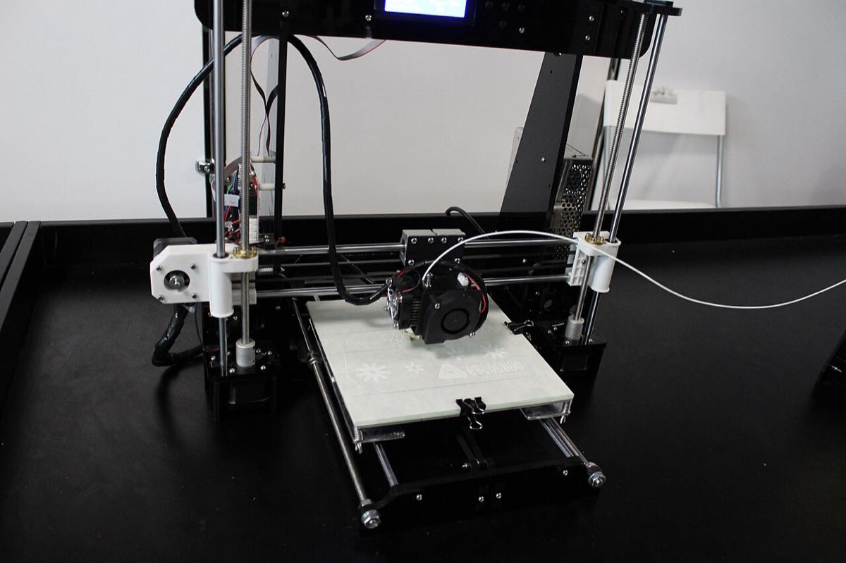 Impressora 3D em operação depositando filamento sobre a mesa de impressão