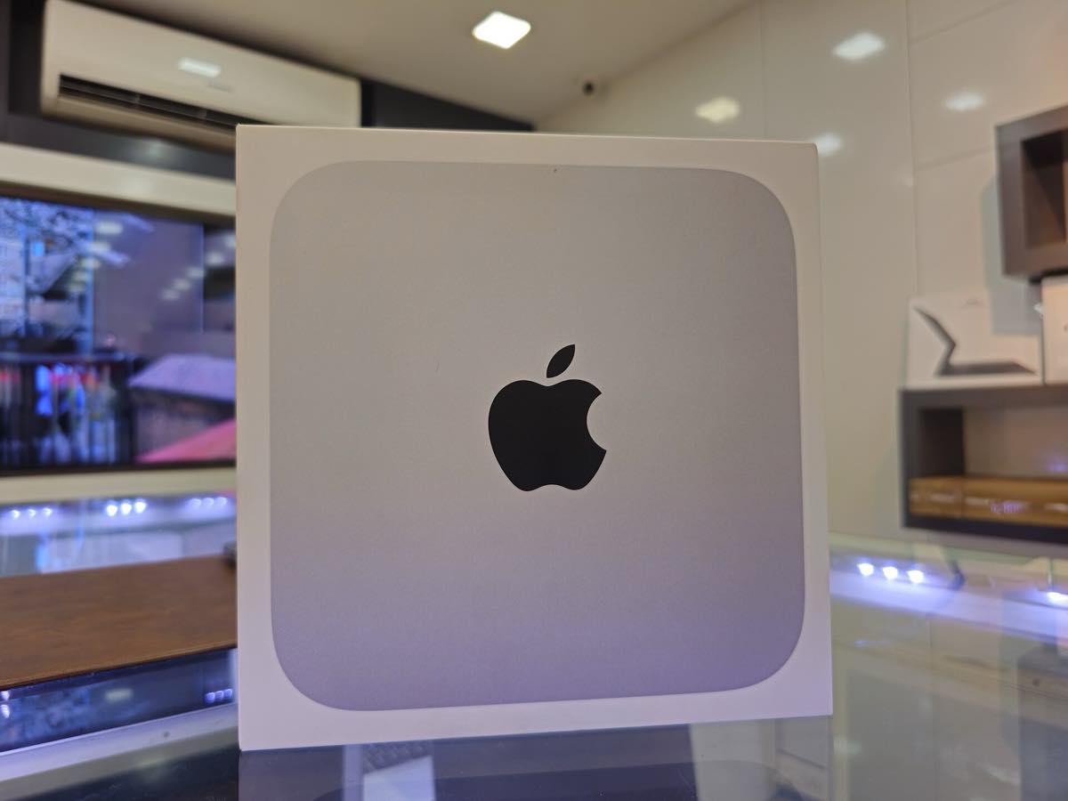 Mac mini, computador de mesa em caixa metálica quadrada e baixa, sobre superfície clara