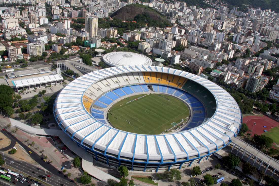 Vista aérea do Estádio do Maracanã, no Rio de Janeiro, com a cobertura branca circular, o gramado verde ao centro e os prédios da cidade ao redor