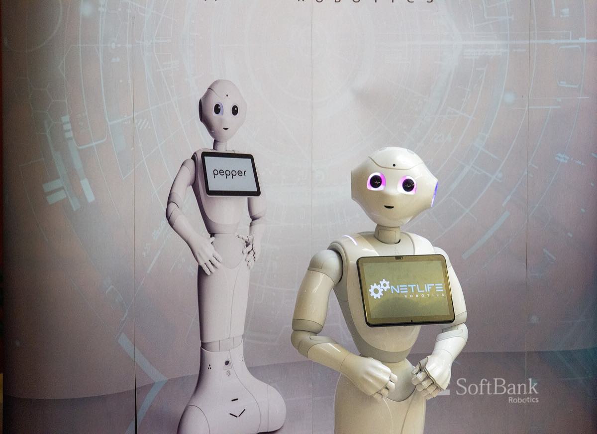 Robô humanóide branco em pé diante de pessoas em um evento
