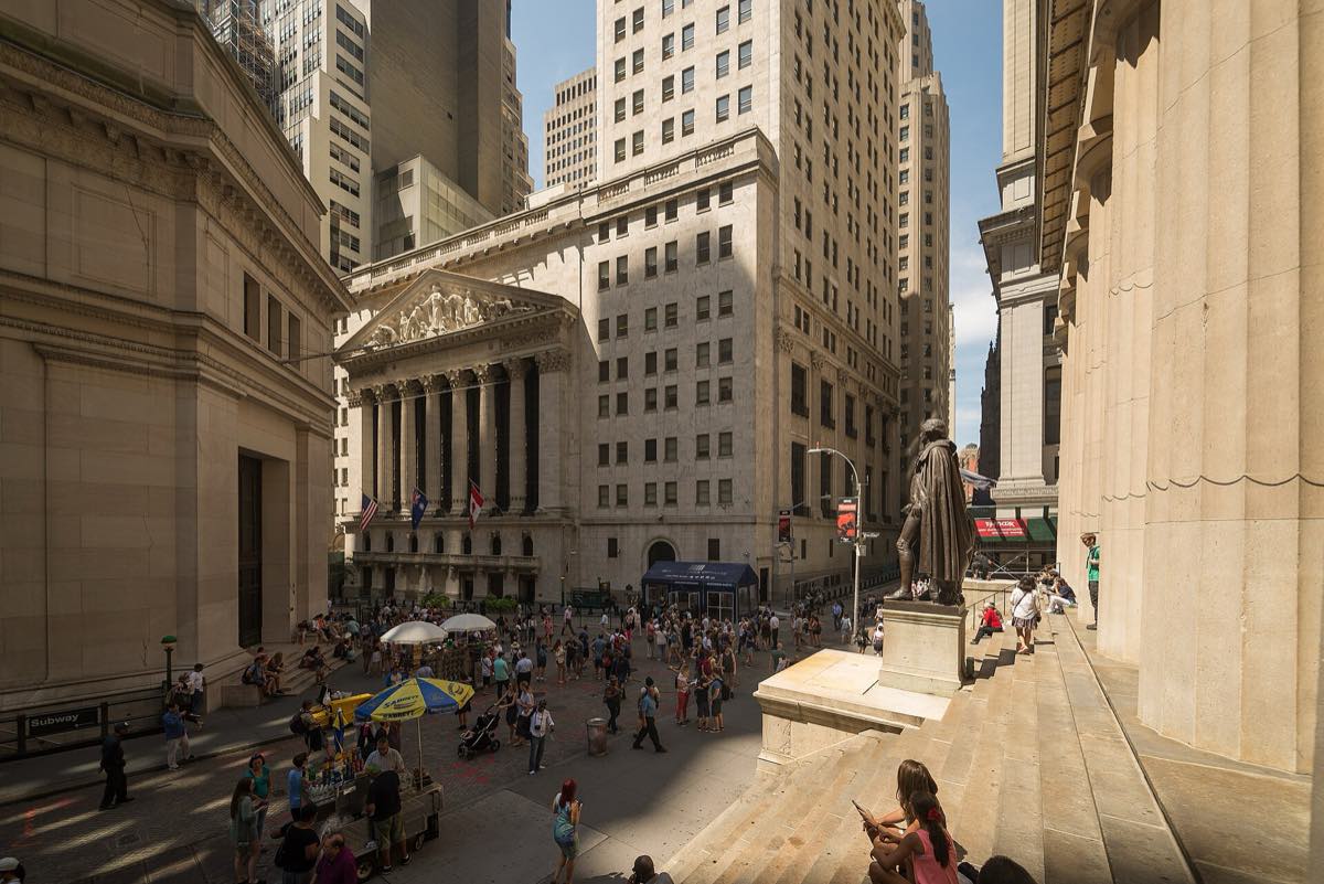 Fachada neoclássica da Bolsa de Valores de Nova York com colunas e bandeira dos Estados Unidos
