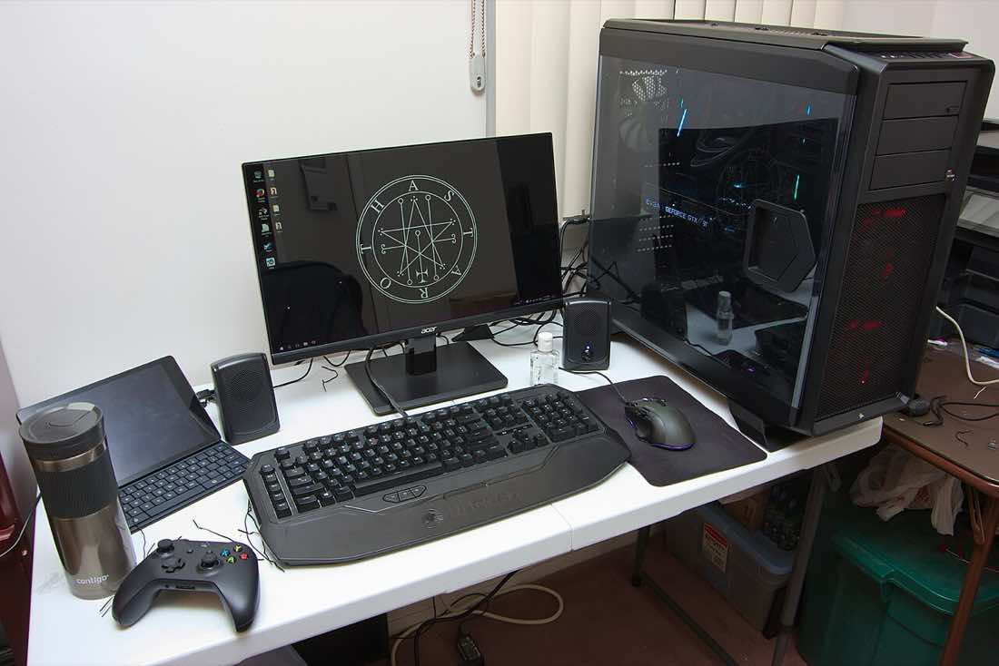 PC de jogos montado sobre uma mesa, com gabinete iluminado, monitor, teclado e periféricos.