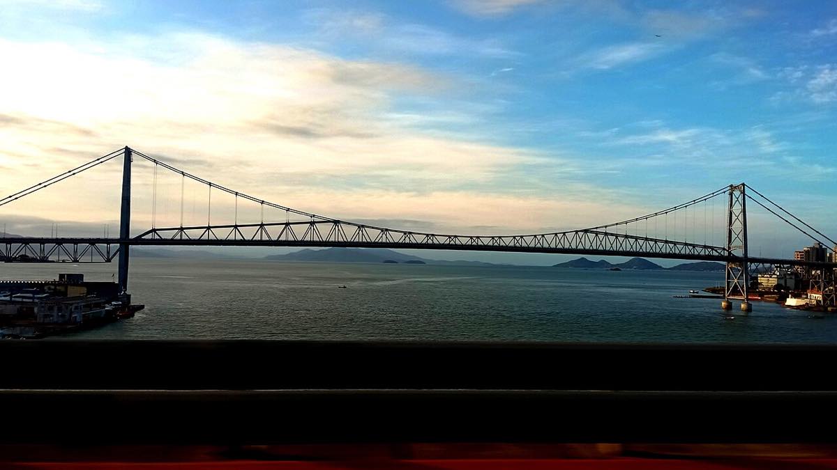 Ponte Hercílio Luz iluminada ao entardecer sobre o mar em Florianópolis