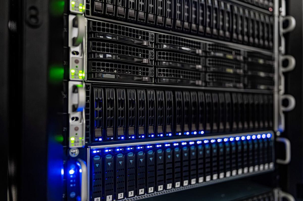 Frente de um rack com servidores empilhados, baias de disco de extração frontal e LEDs azuis e verdes acesos