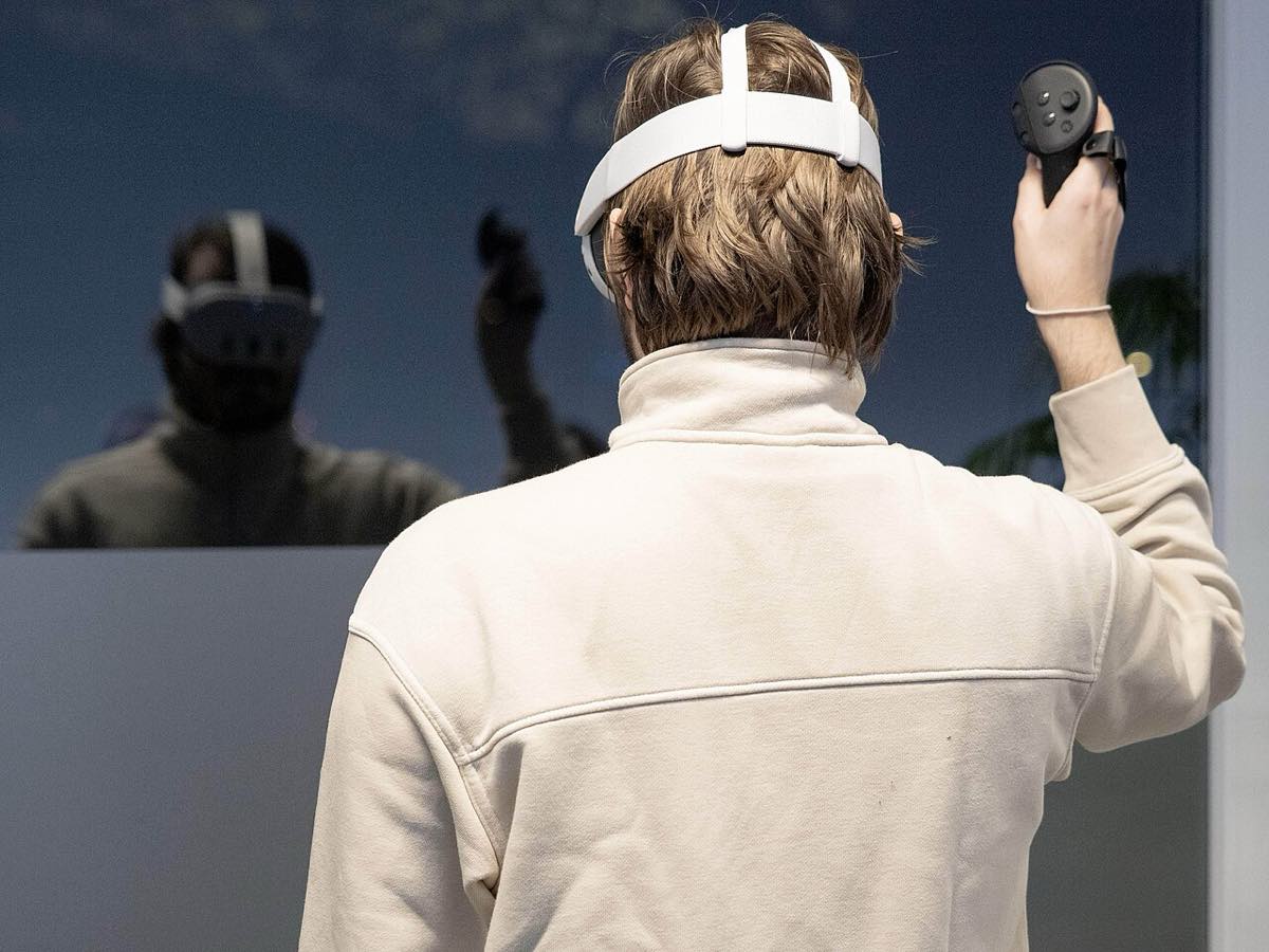 Pessoa usando óculos de realidade virtual, com um controle nas mãos.