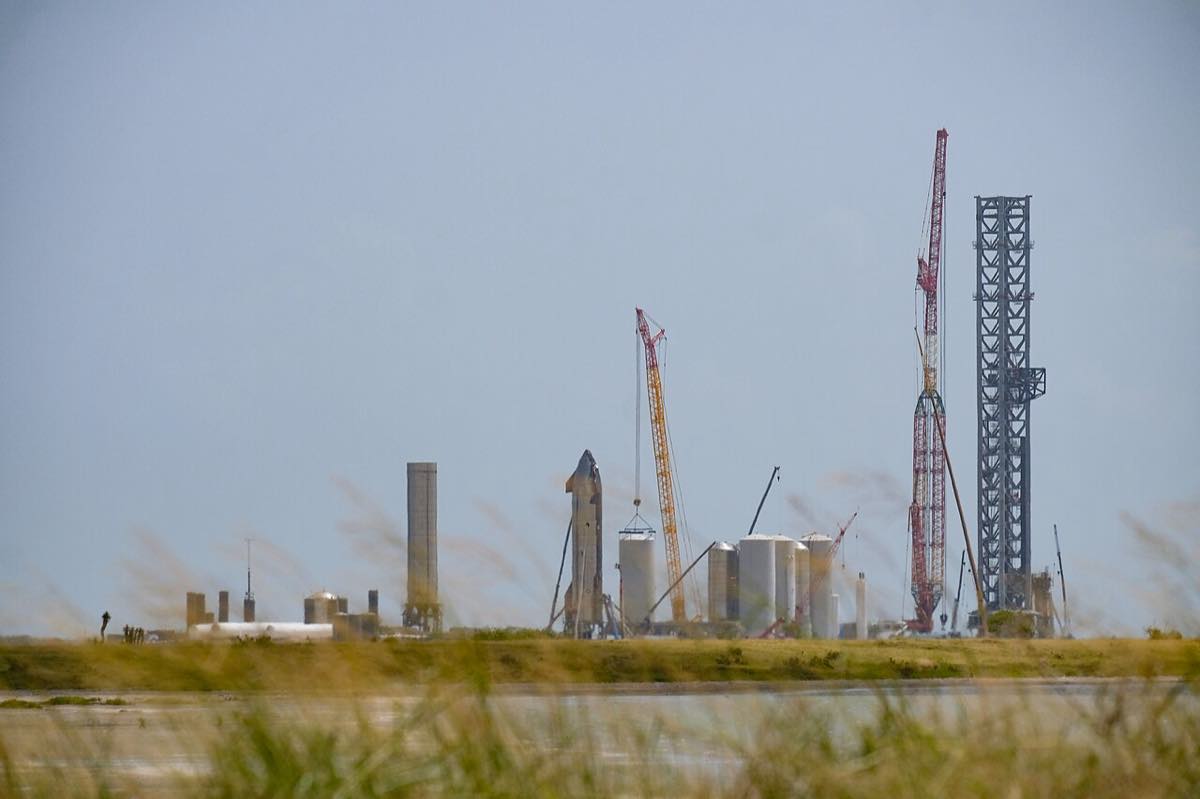 Instalação de lançamento da SpaceX em Starbase, com a nave Starship e a torre de lançamento vista do outro lado da baía