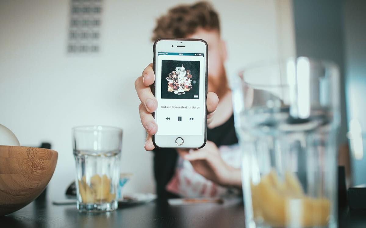 Streaming de música no smartphone: uma pessoa exibe o celular com um aplicativo de música na tela de reprodução. Imagem ilustrativa do tema — não é o app do Deezer.